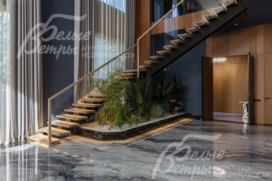 На второй этаж ведёт «парящая» лестница на металлокаркасе с подсветкой, массивными деревянными ступенями и стеклянным ограждением. Рядом с лестницей - каменный сад