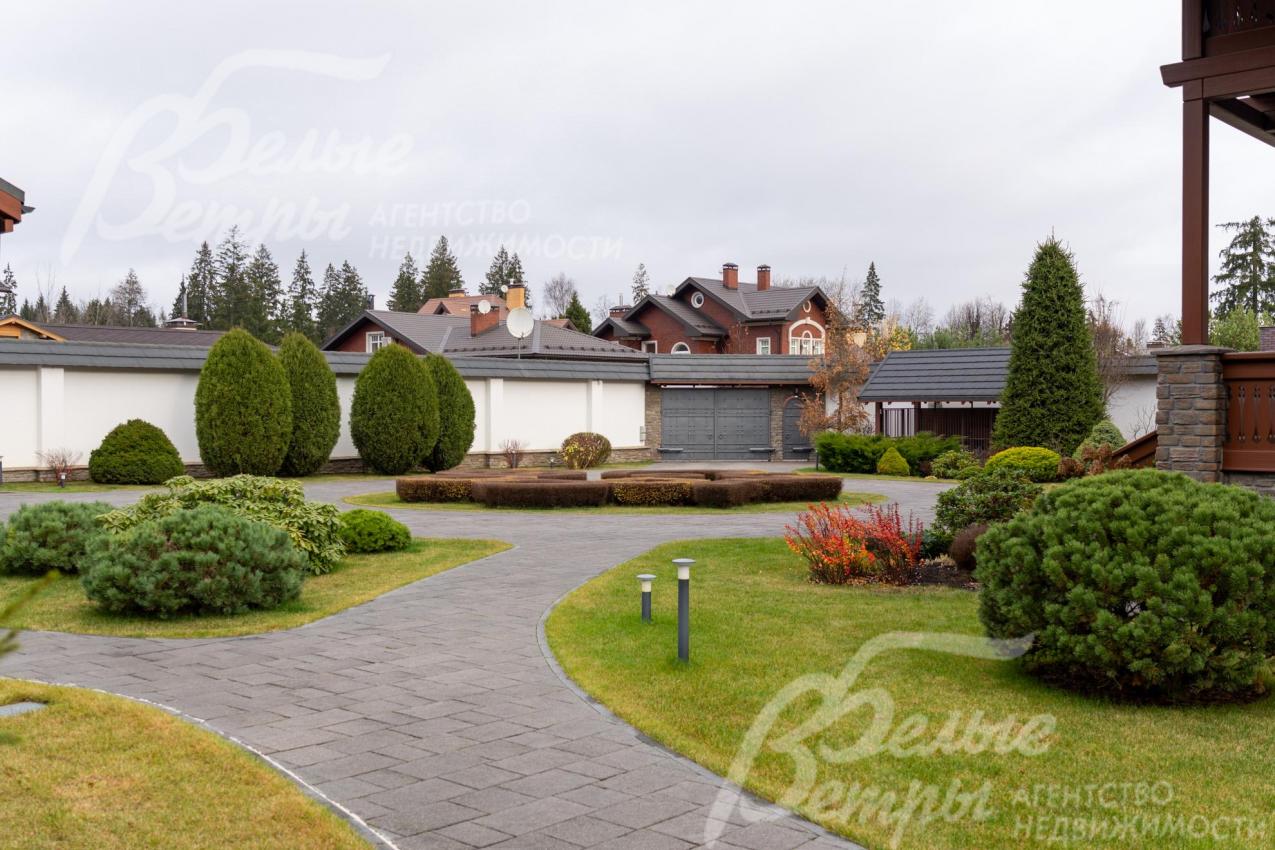 Территория огорожена кирпичным забором высотой 3,5-4 м в стиле дома с белой штукатуркой «короед» с черепичным покрытием