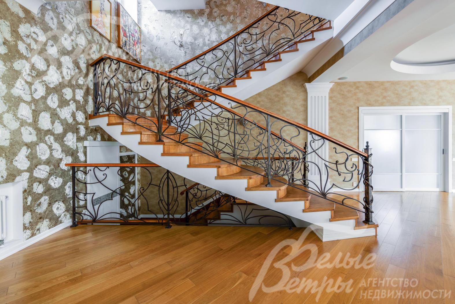 Красивая лестница с дубовыми ступенями и коваными перилами ручной работы.