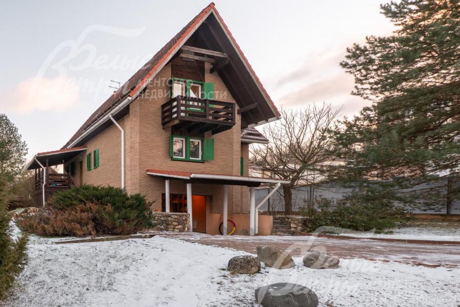 Дом - с крутой двускатной крышей, придающей ему особый шарм, фасад выполнен в тёплых, природных тонах, которые гармонично сочетаются с окружающей зеленью