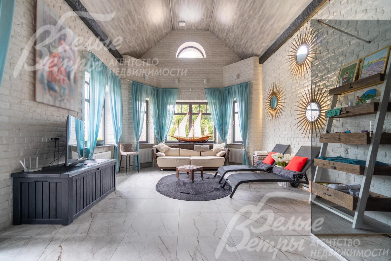 Комната - с высокими скошенными потолками и большими окнами. На стенах — крупные декоративные зеркала в виде солнечных лучей 