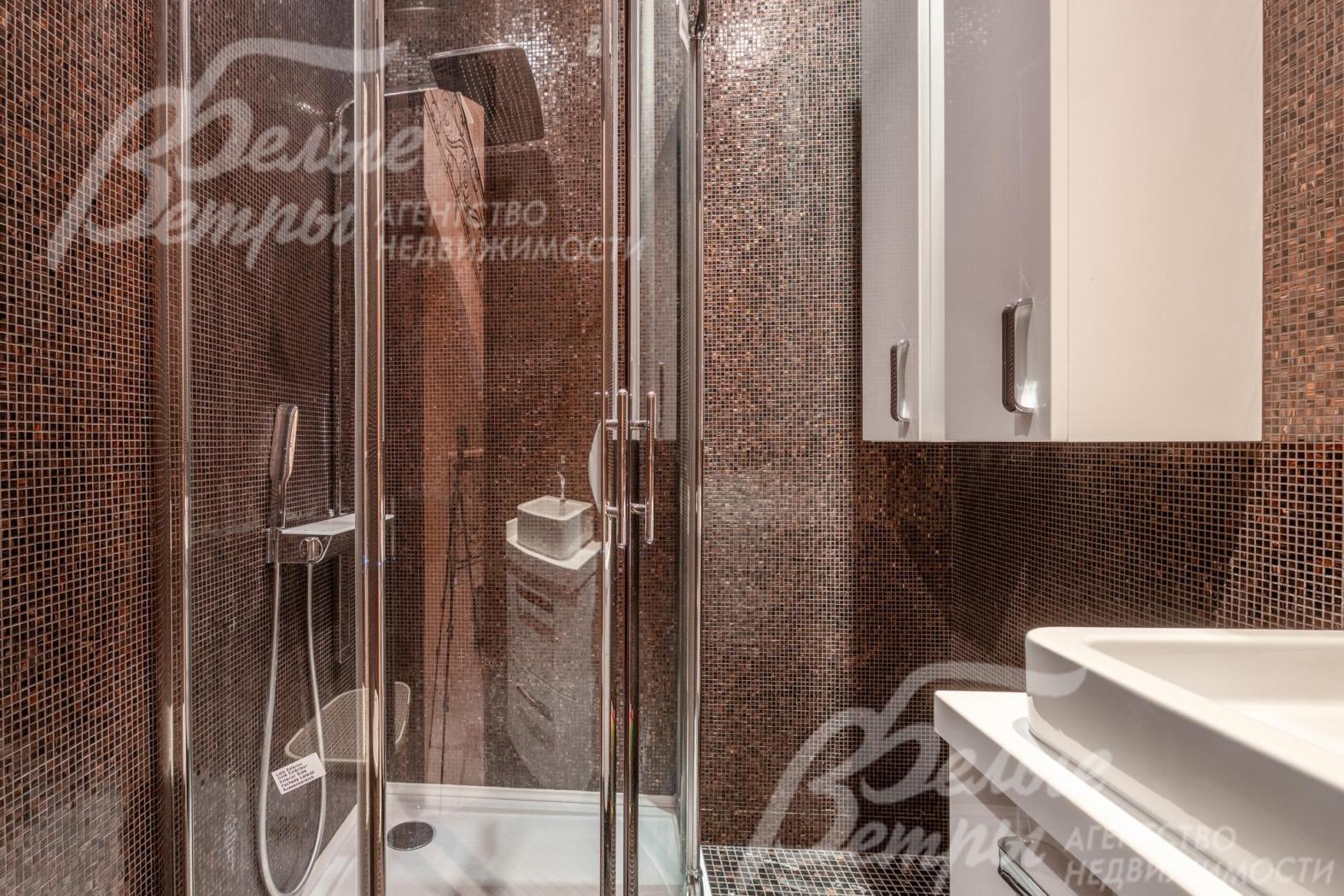 Стена санузла и душевой оформлены коричневой мозаичной плиткой, на полу - керамогранит с подогревом
