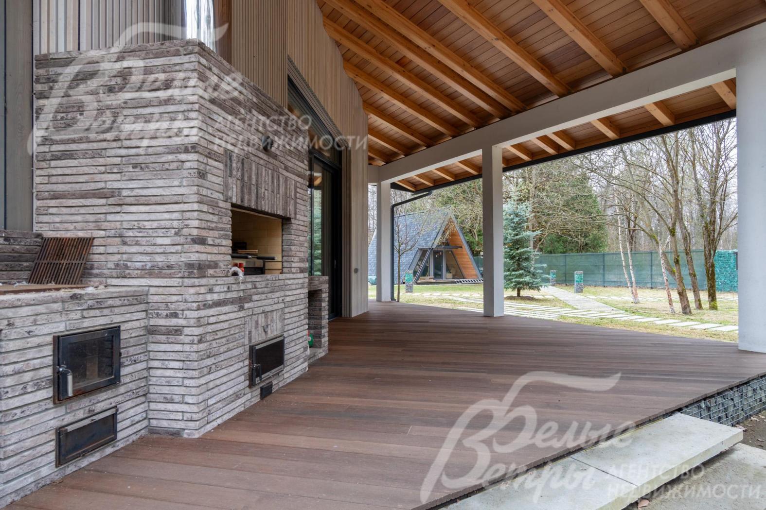 На террасе уложена реечная террасная доска из лиственницы, барбекю-зона - с дровяным камином