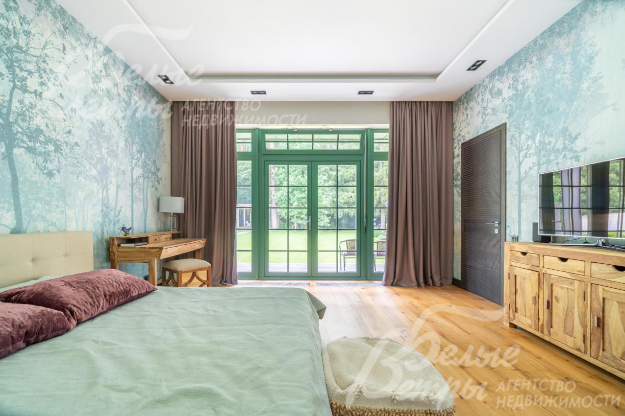 Мастер-спальня на первом этаже с окном в пол и выходом на террасу