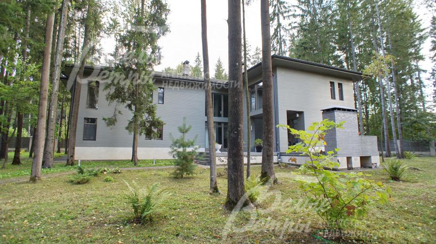 Каменный дом отделан лиственницей и цоколь облицован песчаником