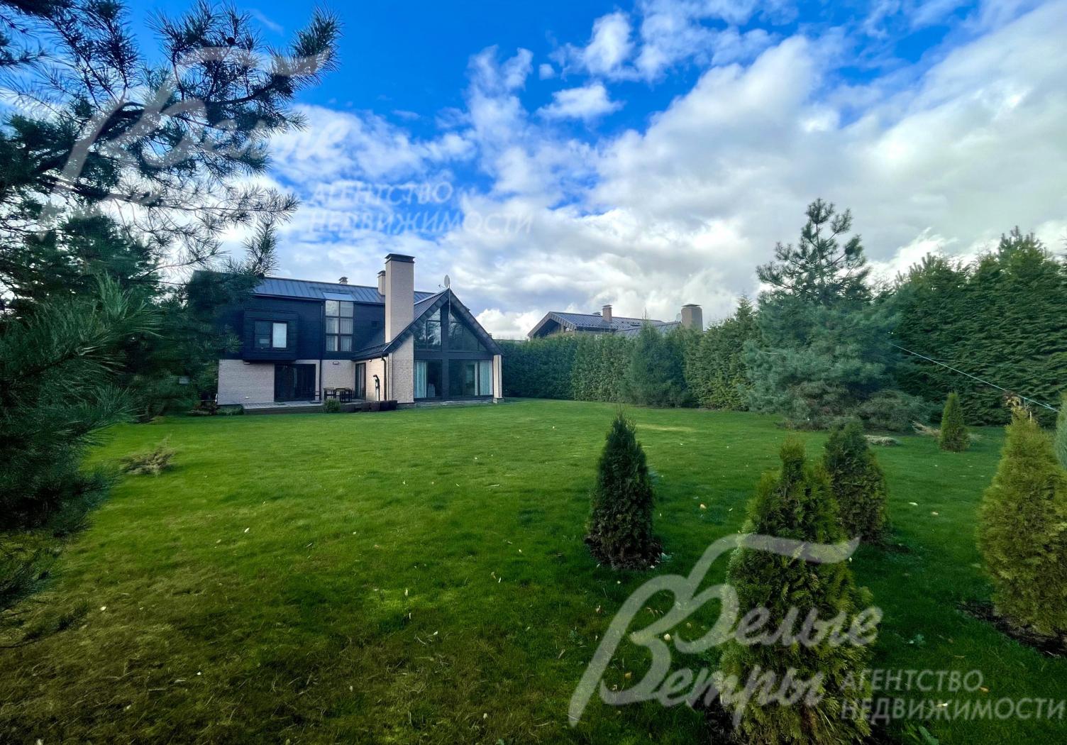 На участке газон, по периметру высажены молодые деревья: туи, сосны