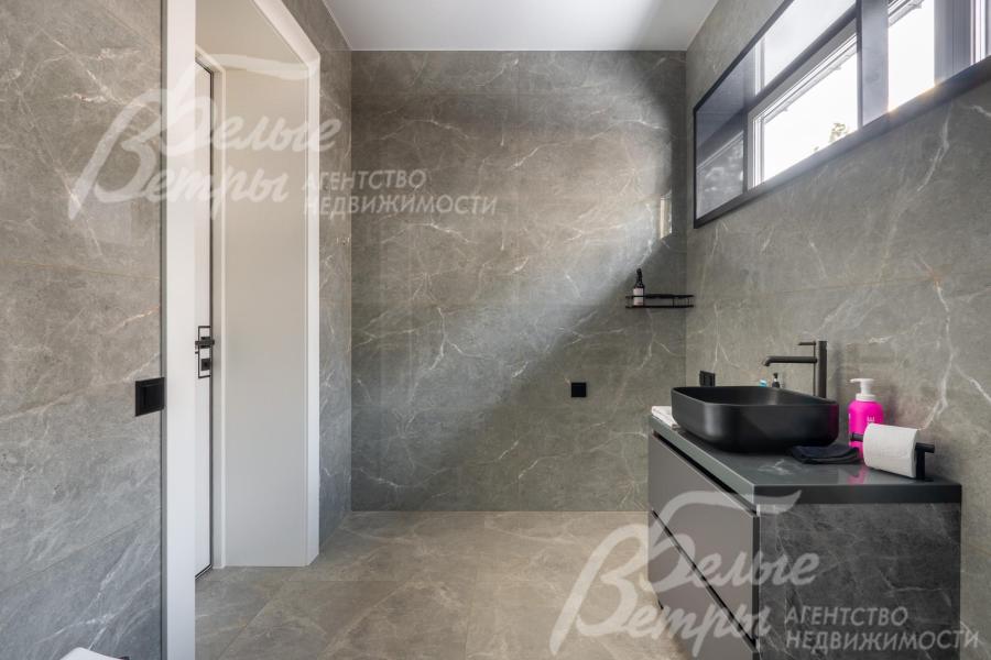 Общий санузел отделан крупноформатным керамогранитом с фактурой под серый мрамор
