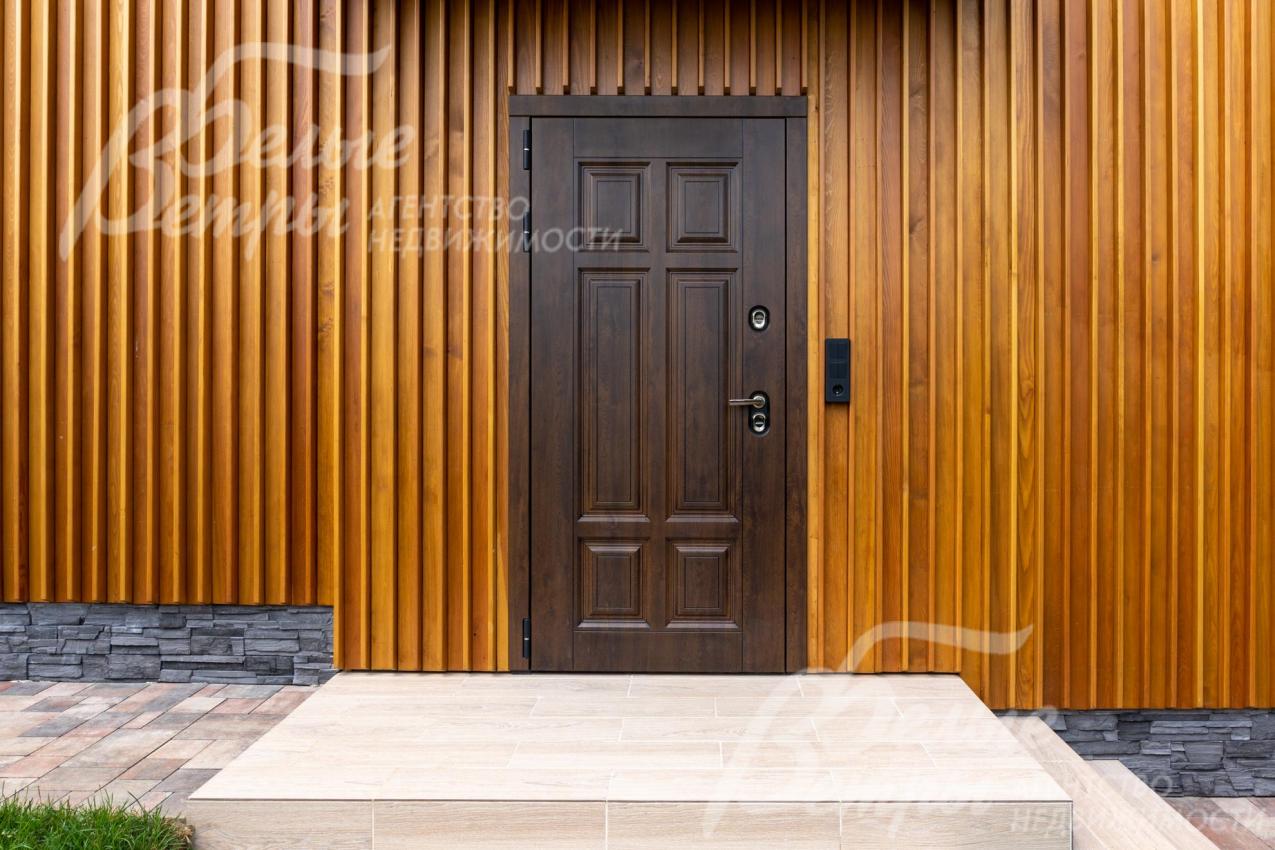 Входная группа в дом: отделка - натуральным планкеном из лиственницы, на цоколе - искусственный камень, у входа уложена плитка