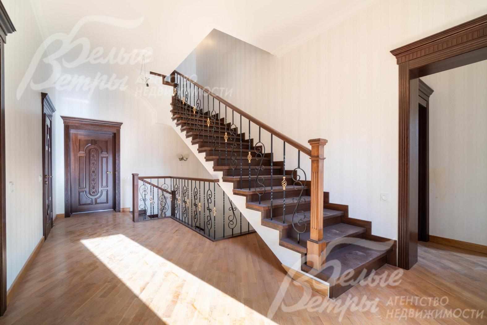 Лестница ведёт на мансардный этаж, её перила сочетают деревянные балясины с коваными элементами, украшенными изящным орнаментом