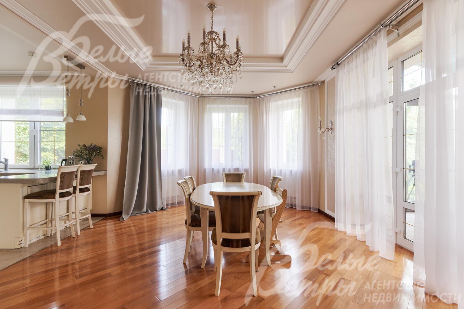 В гостиной много света благодаря большим окнам и остеклённому эркеру. Справа - выход на остеклённую террасу