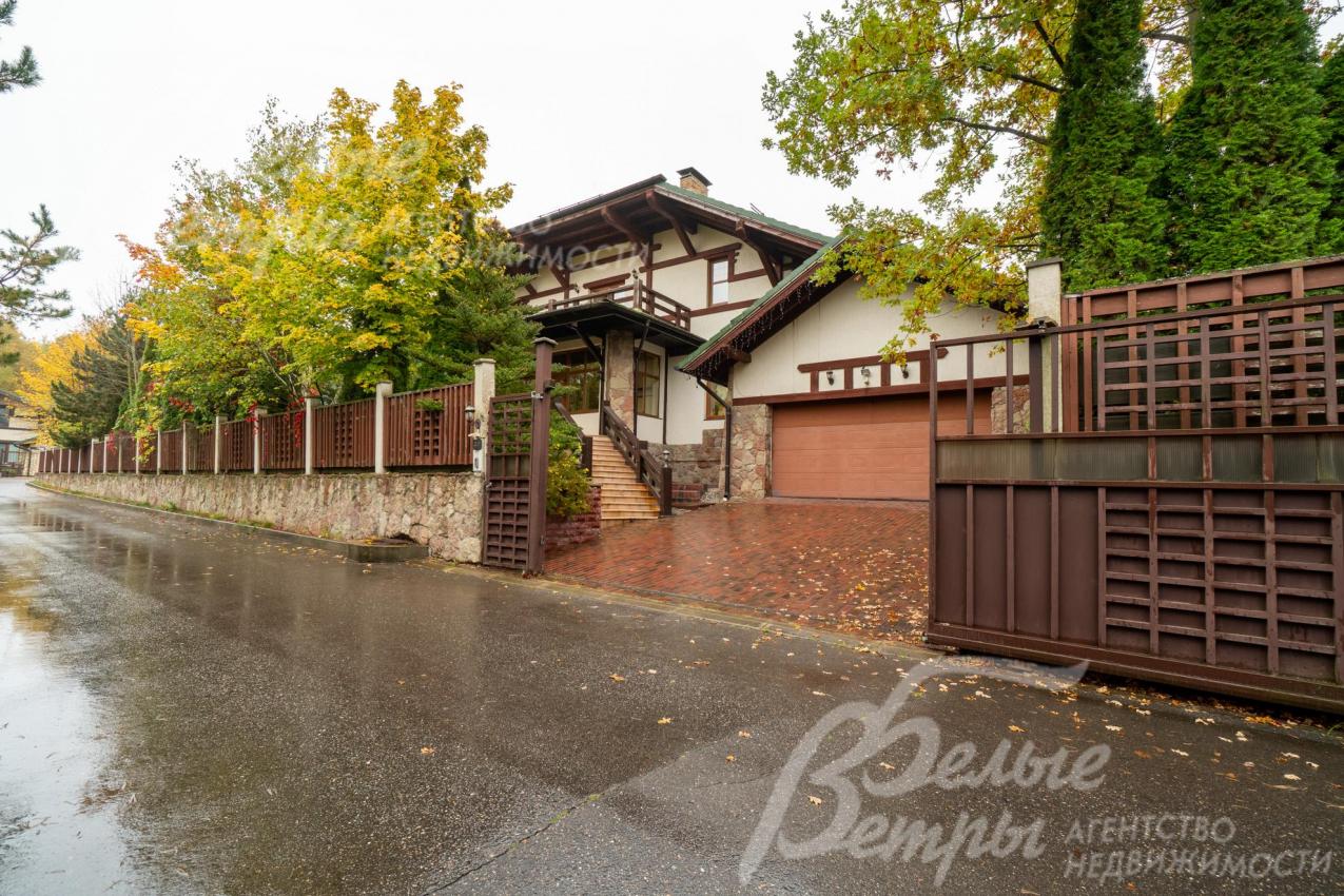 Участок огорожен забором, отделанным натуральным камнем и заполненным деревянными рейками