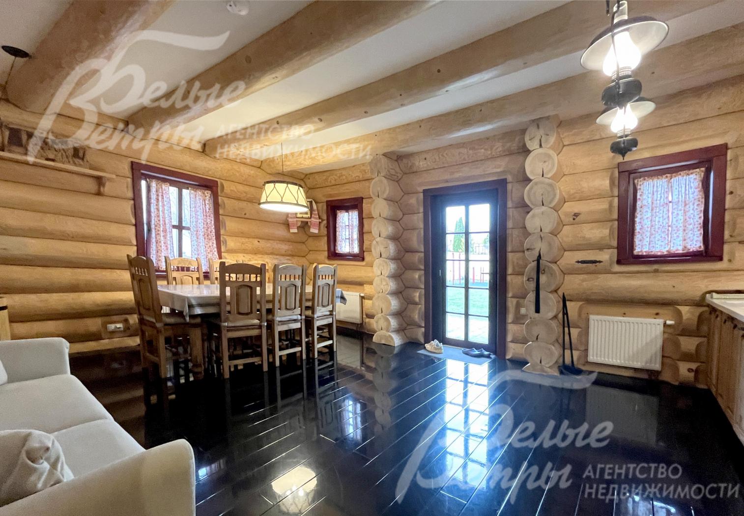 Отделка пола выполнена эффектным чёрным глянцевым ламинатом, на потолке - массивные бревенчатые балки с проёмами белого цвета 