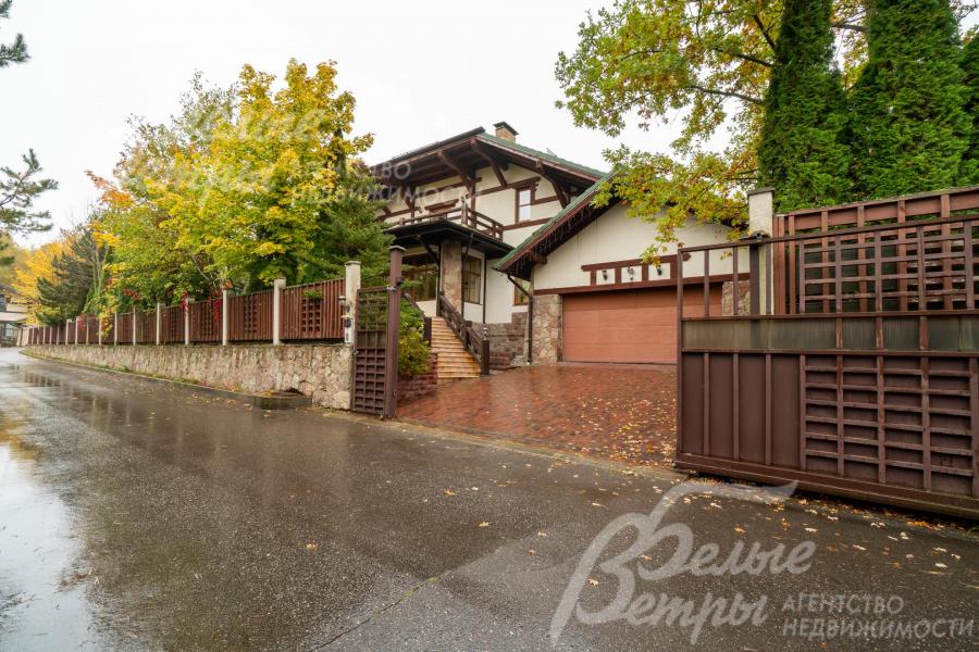 Участок огорожен забором, отделанным натуральным камнем и заполненным деревянными рейками