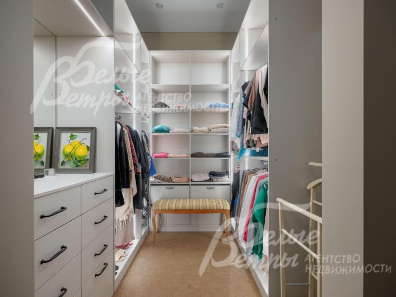 Гардеробная мастер-спальни с системой хранения, удобным пуфом и комодом