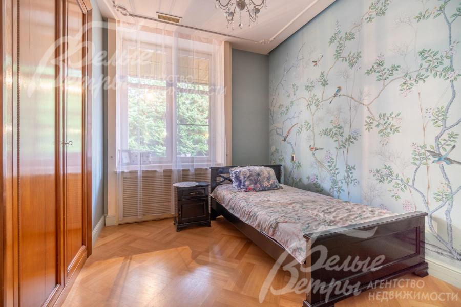 Одна из спален на первом этаже дома со шкафом и кроватью