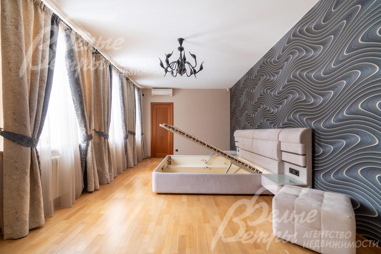 Мастер-спальня на втором этаже: кровать расположена напротив трёх больших окон, декорированных элегантными шторами