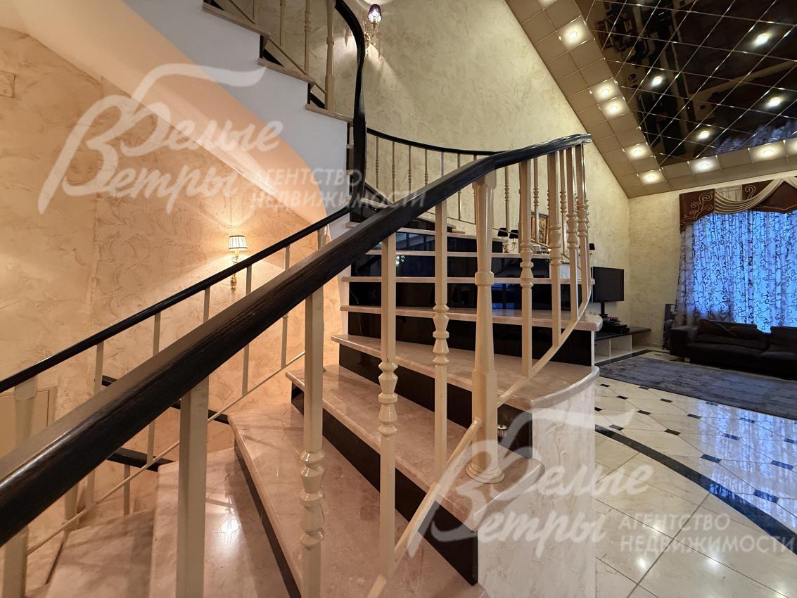 Рядом с гостиной - каминный зал со вторым светом и винтовой лестницей на второй этаж