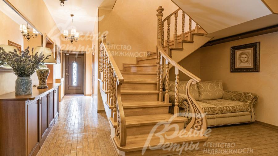 Лестница монолитная отделана светлым деревом с деревянными перилами и резными балясинами