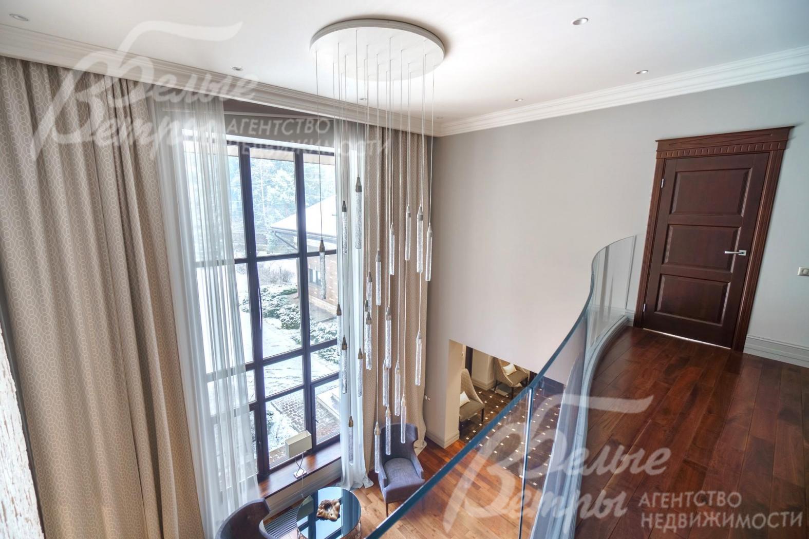 Прозрачное изогнутое ограждение и люстра продуманного дизайна позволяют без препятствий видеть лес.