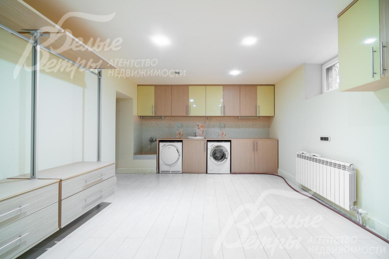 Постирочная на цокольном этаже оборудована стиральной и сушильной машинами и мебелью