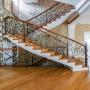 Красивая лестница с дубовыми ступенями и коваными перилами ручной работы.