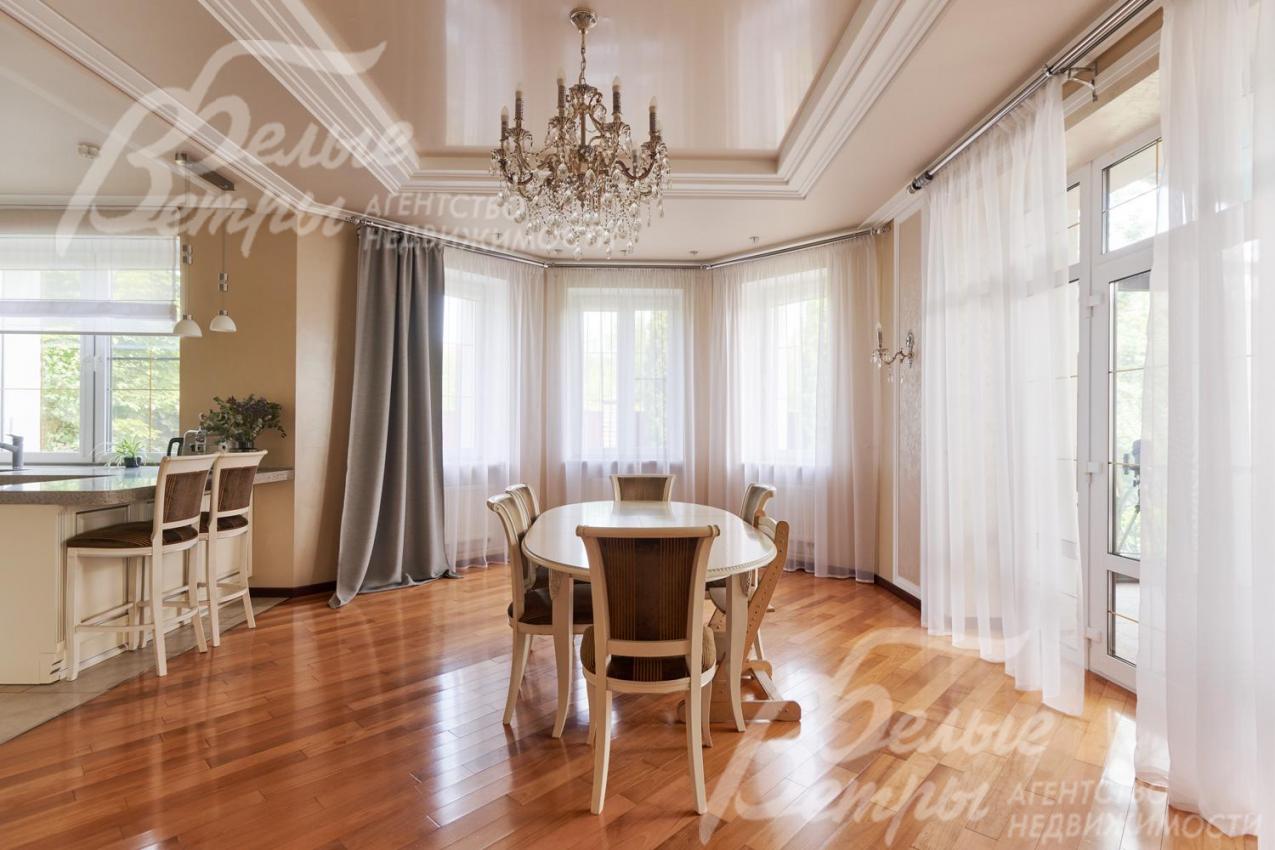 В гостиной много света благодаря большим окнам и остеклённому эркеру. Справа - выход на остеклённую террасу