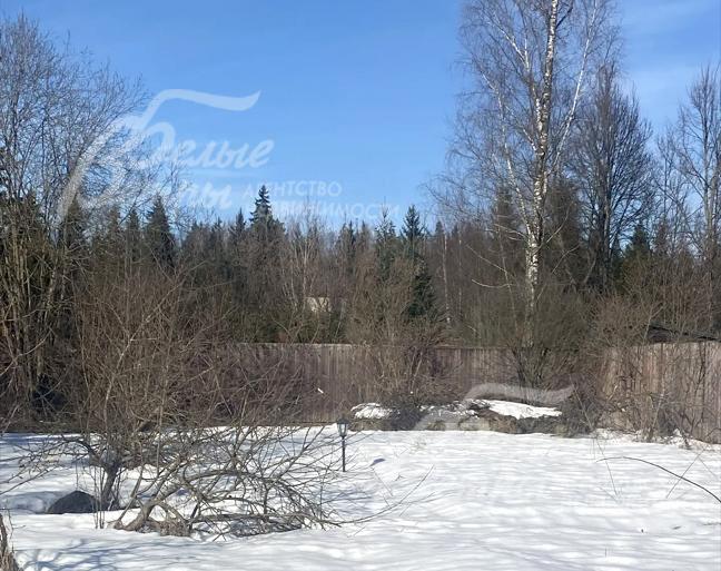 Территория участка огорожена забором с кирпичными столбами и деревянным заполнением