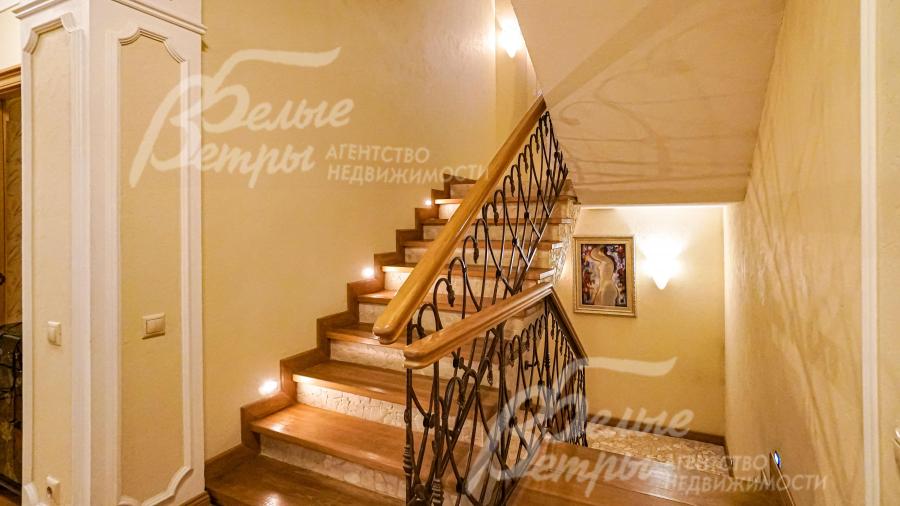 Изящная удобная лестница с дубовыми ступенями, с перилами с художественной ковкой