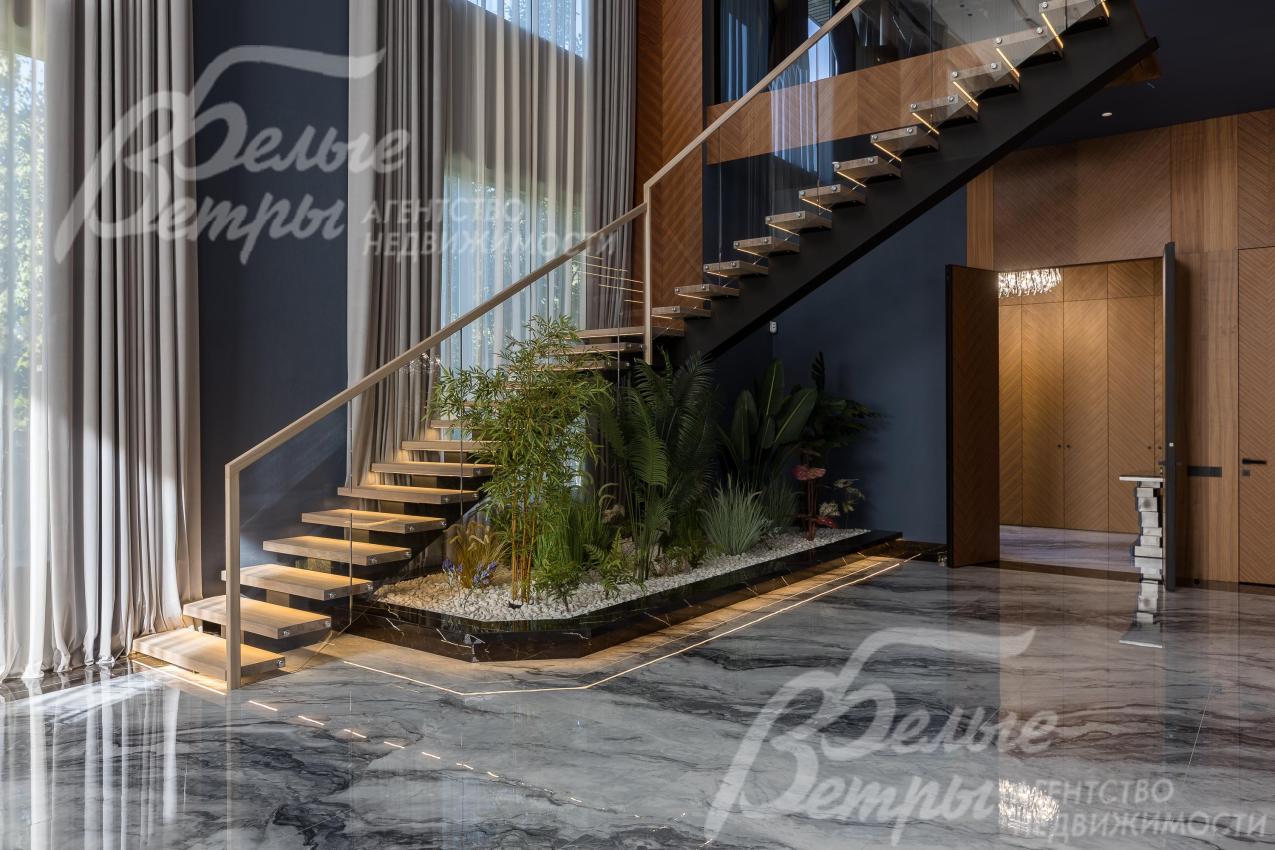 На второй этаж ведёт «парящая» лестница на металлокаркасе с подсветкой, массивными деревянными ступенями и стеклянным ограждением. Рядом с лестницей - каменный сад