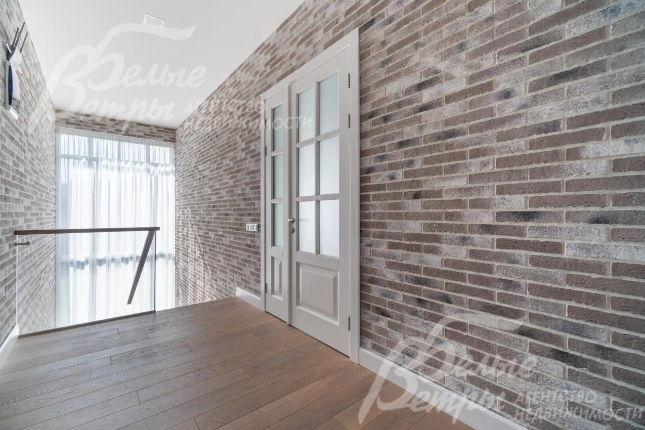Холл второго этажа с декоративной отделкой стен "под кирпич" и белыми дверями из массива дуба