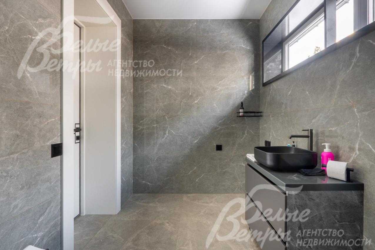 Общий санузел отделан крупноформатным керамогранитом с фактурой под серый мрамор