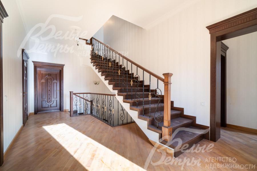 Лестница ведёт на мансардный этаж, её перила сочетают деревянные балясины с коваными элементами, украшенными изящным орнаментом