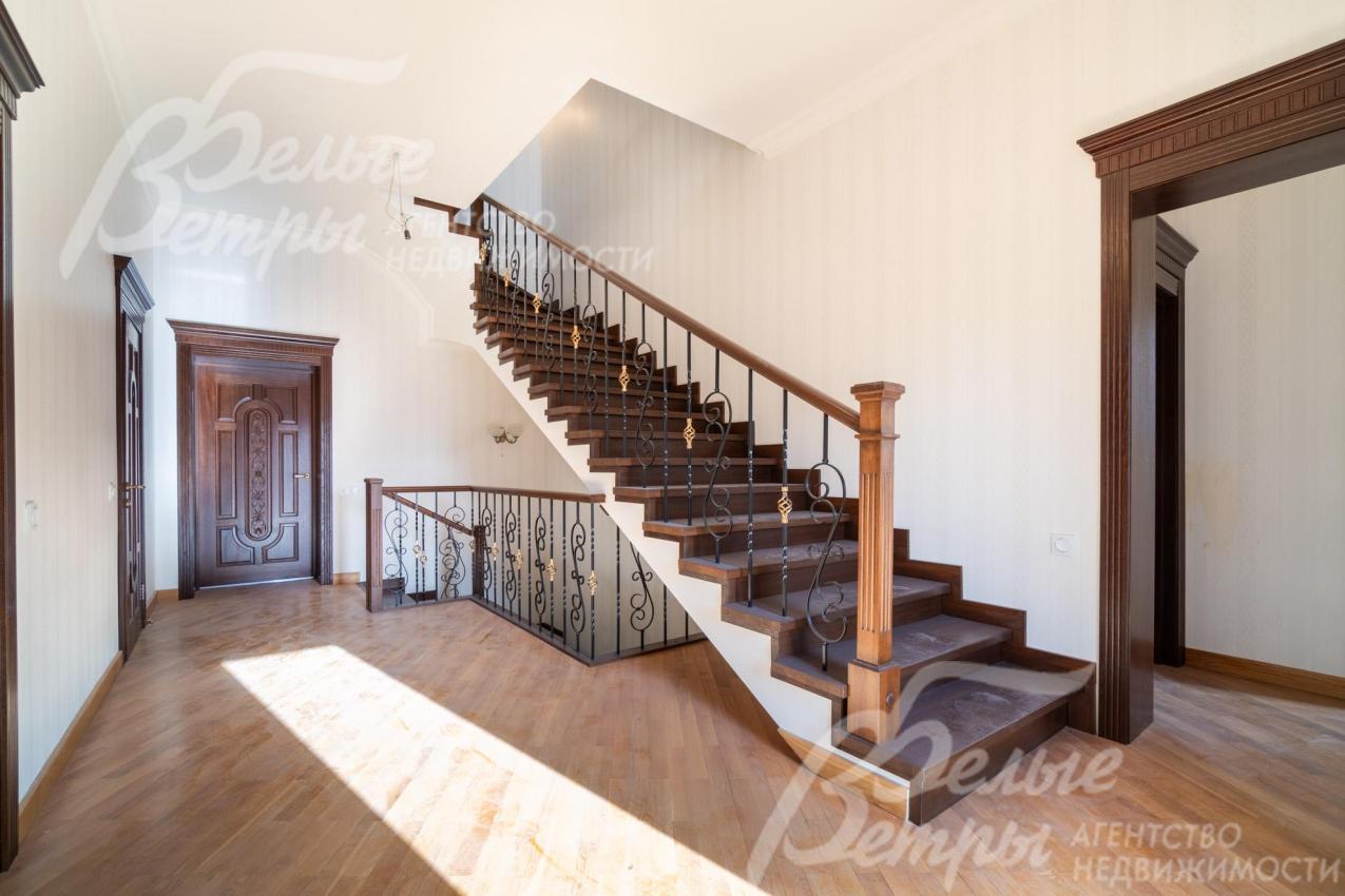 Лестница ведёт на мансардный этаж, её перила сочетают деревянные балясины с коваными элементами, украшенными изящным орнаментом