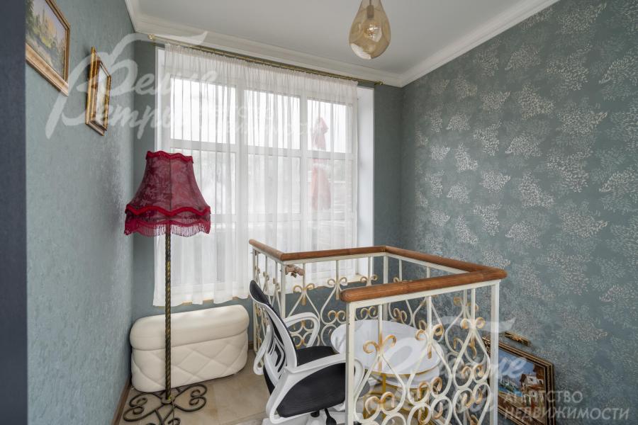 Лестница с изящным кованным ограждением и перилами из лиственницы.