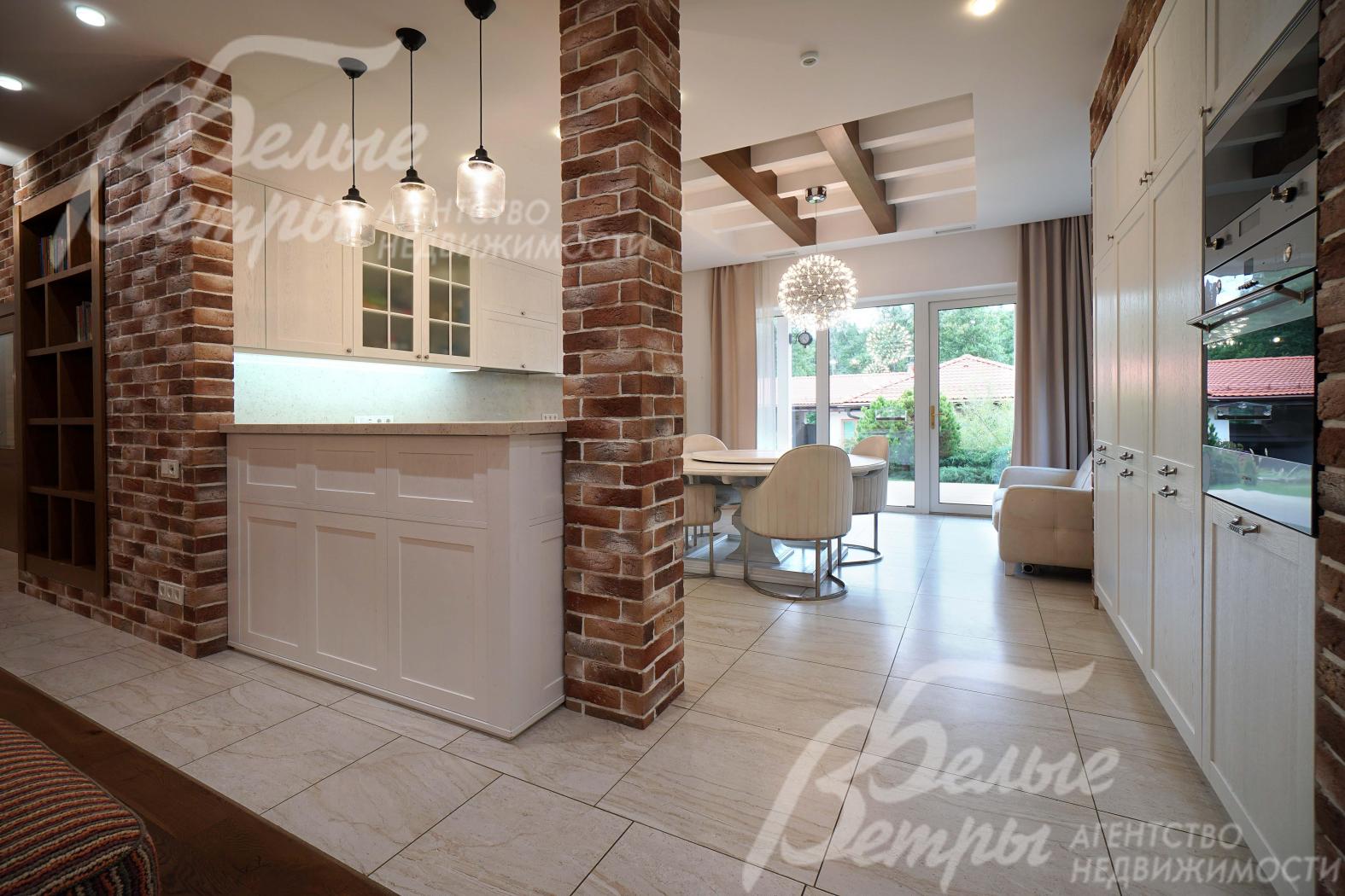 Пространство у входа на кухню зонировано барной стойкой и декоративной колонной