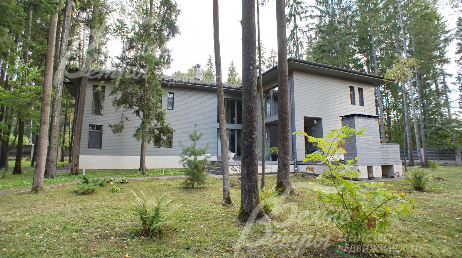 Каменный дом отделан лиственницей и цоколь облицован песчаником