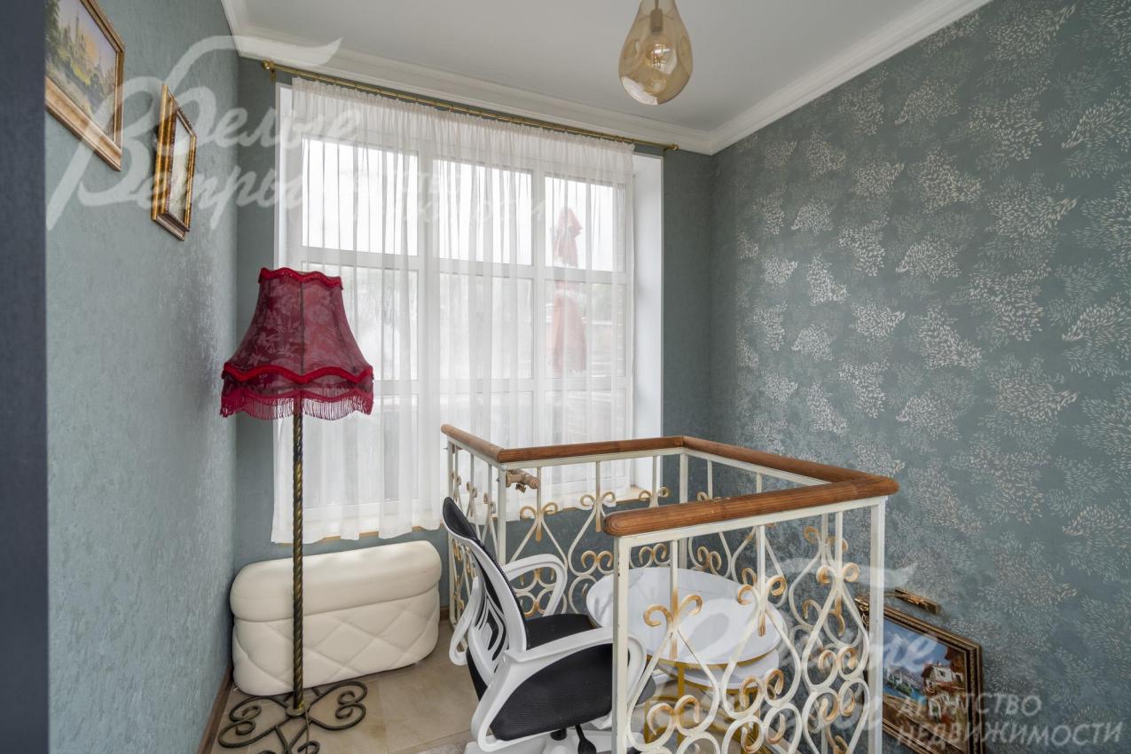 Лестница с изящным кованным ограждением и перилами из лиственницы.