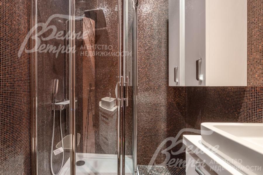 Стена санузла и душевой оформлены коричневой мозаичной плиткой, на полу - керамогранит с подогревом