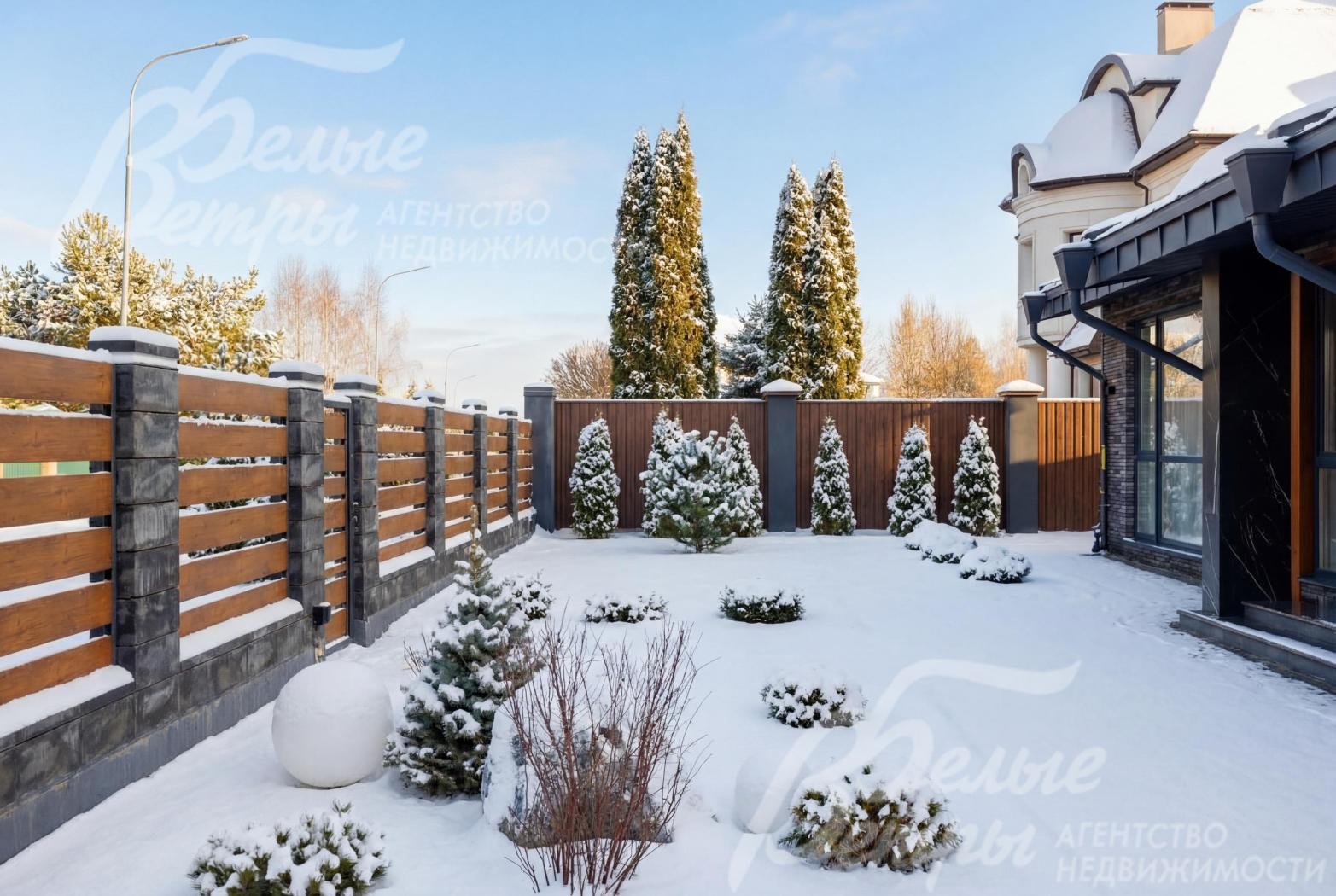 На участке с ландшафтным дизайном высажены деревья, декоративные кустарники