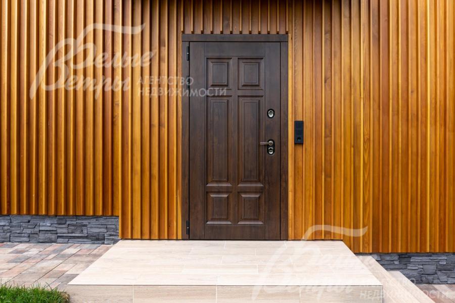 Входная группа в дом: отделка - натуральным планкеном из лиственницы, на цоколе - искусственный камень, у входа уложена плитка