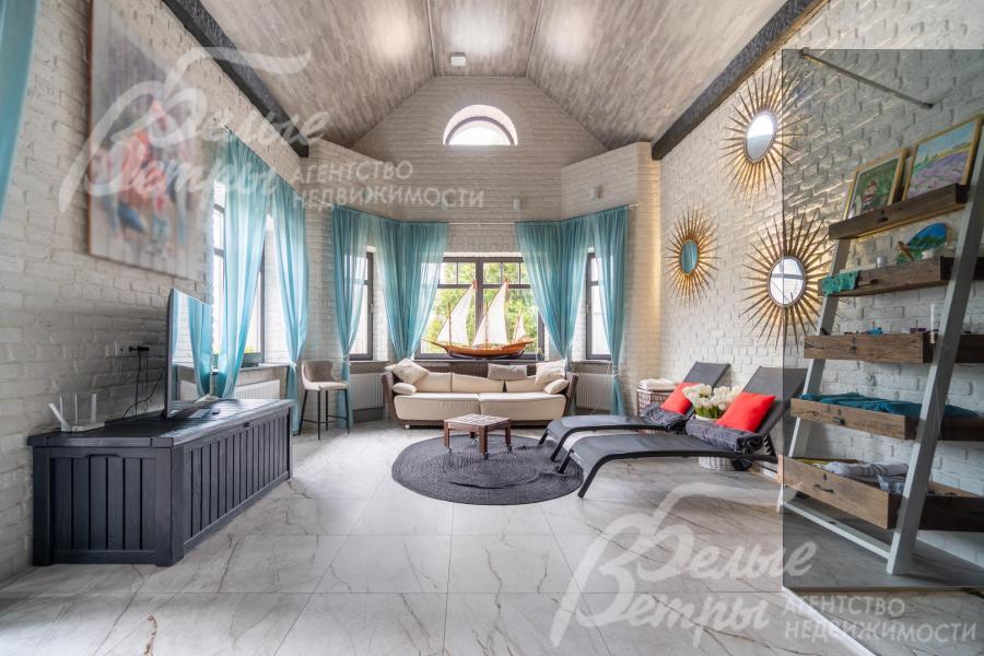 Комната - с высокими скошенными потолками и большими окнами. На стенах — крупные декоративные зеркала в виде солнечных лучей 