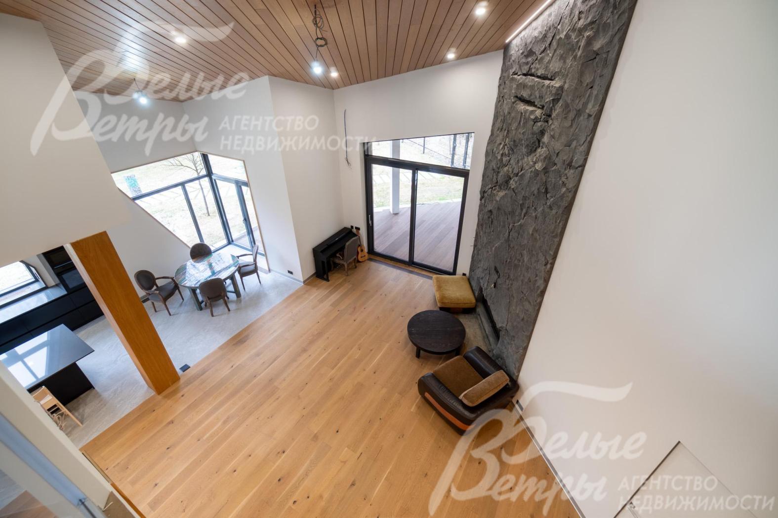 Гостиная - со вторым светом (высота потолков до 7,4 м), из неё - выход на террасу через портал с алюминиевым профилем оттенка антрацит